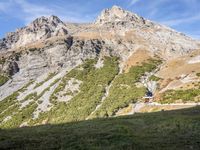 a man standing in a valley with the mountains in the background taking a picture of his dog