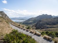 an old mountain road curves along a valley in the desert, near mountains and ocean