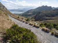 an old mountain road curves along a valley in the desert, near mountains and ocean