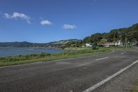 a motorcycle is parked by the edge of the road beside the water and hills in the background