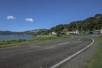 a motorcycle is parked by the edge of the road beside the water and hills in the background