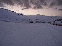 ski lift is sitting on the snow near the mountains at dusk overlooking a ski slope