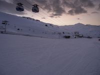 ski lift is sitting on the snow near the mountains at dusk overlooking a ski slope