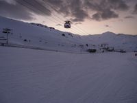 ski lift is sitting on the snow near the mountains at dusk overlooking a ski slope