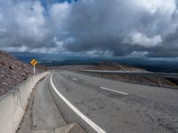 a highway with a curve of road near mountains and a highway sign on the side