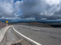 a highway with a curve of road near mountains and a highway sign on the side