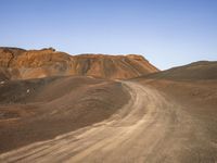 the dirt road in front of a mountain in a barren area is mostly empty for people to take pictures