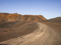 the dirt road in front of a mountain in a barren area is mostly empty for people to take pictures