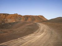 the dirt road in front of a mountain in a barren area is mostly empty for people to take pictures