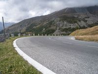 the road curves as the mountains line up in the background behind it in the clouds