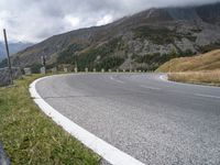 the road curves as the mountains line up in the background behind it in the clouds