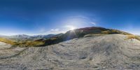 there is a very high up mountain with a sun in the background and there are some big rocks