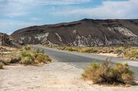 the road stretches into a large mountainous, barren area in the desert area of the deserts