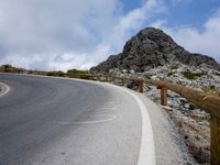 a curved road stretches out into the sky at a distance from the edge of the hill