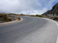 a curved road stretches out into the sky at a distance from the edge of the hill