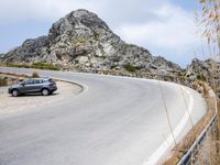 a curved road stretches out into the sky at a distance from the edge of the hill