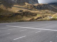 the person is standing on a skateboard on a paved road in a mountainous area