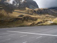 the person is standing on a skateboard on a paved road in a mountainous area