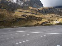 the person is standing on a skateboard on a paved road in a mountainous area