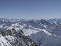 a person on a ski mountain overlooking the mountains in the wintertime with blue skies