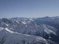 a person on a ski mountain overlooking the mountains in the wintertime with blue skies