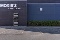 a picture of the outside of a restaurant called moxies grill bar, near a road