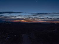 a dark street is shown in the middle of this view at sunset with a mountain below