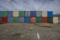 multicolored containers sitting against a cloudy blue sky in front of a dry area