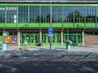 a building with a sign near an empty area in front of it with green walls and windows