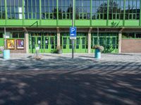 a building with a sign near an empty area in front of it with green walls and windows