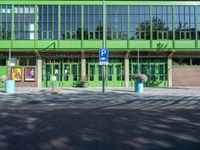 a building with a sign near an empty area in front of it with green walls and windows