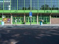 a building with a sign near an empty area in front of it with green walls and windows