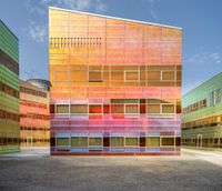 an orange and blue building with windows that have a rainbow pattern on the outside and two green buildings on the inside