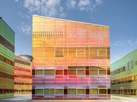 an orange and blue building with windows that have a rainbow pattern on the outside and two green buildings on the inside