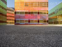 an orange and blue building with windows that have a rainbow pattern on the outside and two green buildings on the inside