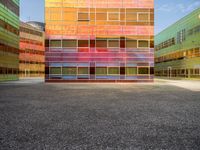 an orange and blue building with windows that have a rainbow pattern on the outside and two green buildings on the inside