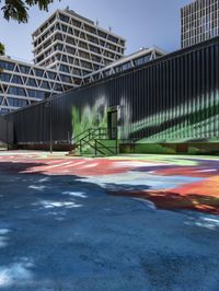 an outside mural with bright colours is painted on a park bench in front of large building