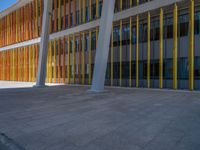 a concrete structure made into rows of orange and yellow poles are on a cement sidewalk