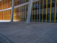 a concrete structure made into rows of orange and yellow poles are on a cement sidewalk