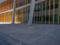 a concrete structure made into rows of orange and yellow poles are on a cement sidewalk