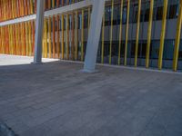 a concrete structure made into rows of orange and yellow poles are on a cement sidewalk