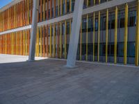 a concrete structure made into rows of orange and yellow poles are on a cement sidewalk