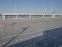 a red cross marks painted on the pavement on a runway at an airport with a plane parked at it and warehouse buildings