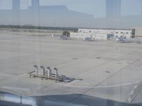 a red cross marks painted on the pavement on a runway at an airport with a plane parked at it and warehouse buildings