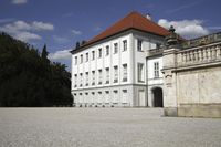 a very large and pretty white building in front of some trees and blue skies in the day