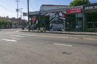 the street is empty and there are no traffic on it at all here, and the buildings are covered in a mural