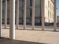 a group of pillars, sidewalk, and sidewalk lamps on a sunny day in a city