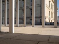 a group of pillars, sidewalk, and sidewalk lamps on a sunny day in a city