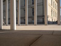 a group of pillars, sidewalk, and sidewalk lamps on a sunny day in a city