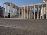 a row of columns is on the street by the building near it on a sunny day